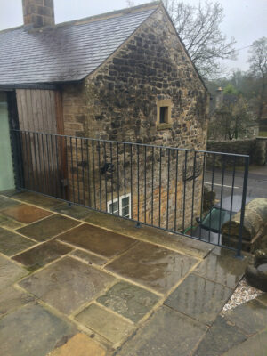 A simple black safety railing on patio area (by Derbyshire Dales Engineering)