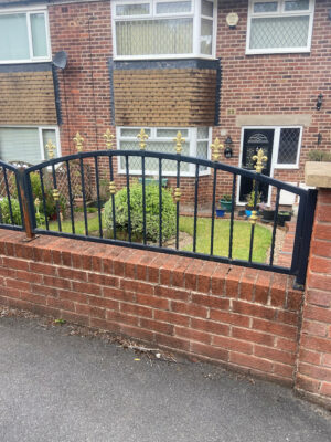 An arched, attractive railing atop a red brick wall (by Derbyshire Dales Engineering)